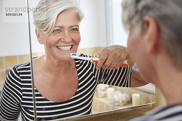 Spiegelbild der Frau beim Zähneputzen