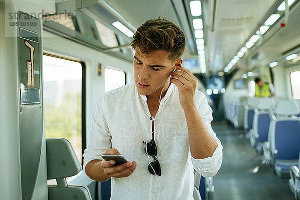 Junger Mann mit einem Smartphone im Zug