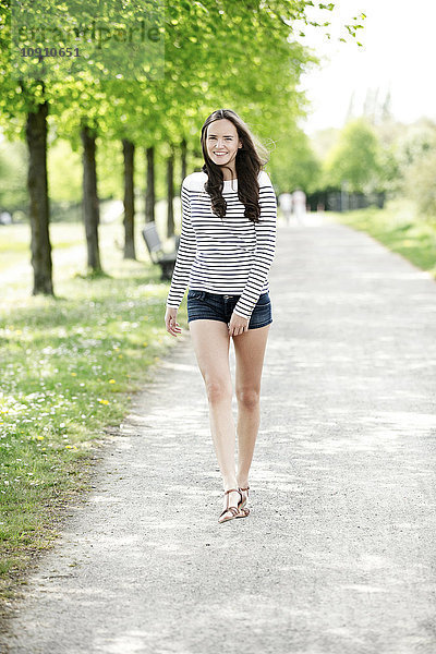 Porträt einer lächelnden jungen Frau in gestreiftem Sweatshirt und Hotpants