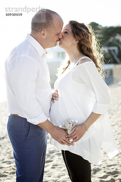 Spanien  Mallorca  schwangere Frau küsst Mann am Strand