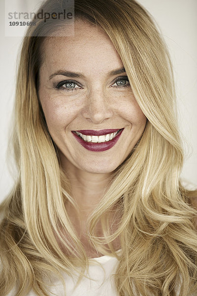Porträt einer lächelnden blonden Frau mit roten Lippen