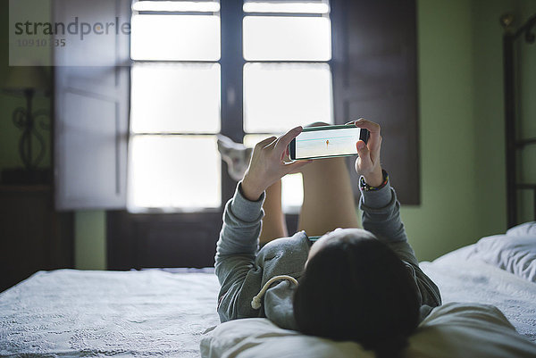 Frau im Bett liegend mit Smartphone