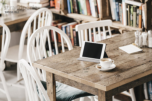 Tisch im Café mit Tasse Kaffee und digitalem Tablett