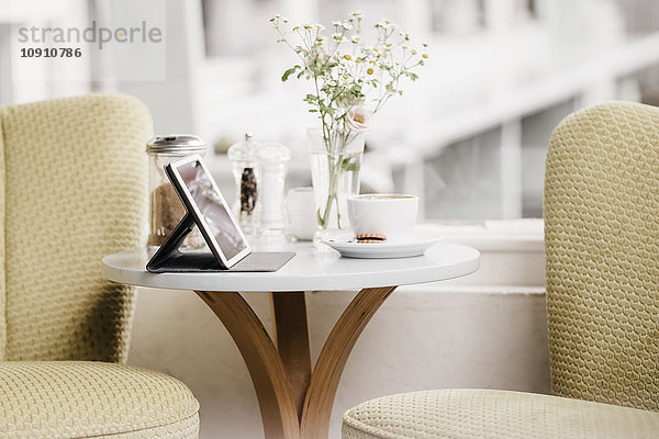 Tisch im Café mit Tasse Kaffee und digitalem Tablett