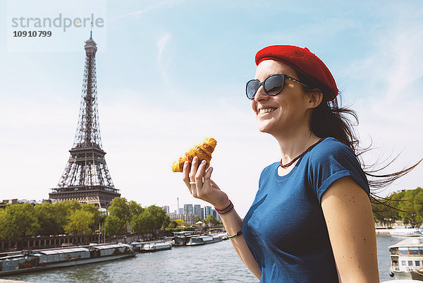 Frankreich  Paris  Frau mit Croissant vor der Seine und Eiffelturm