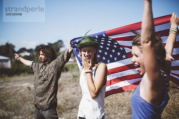 Drei sorglose Hippies mit US-Flagge in der Natur