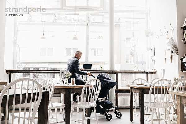 Geschäftsmann sitzend im Café mit Kinderwagen