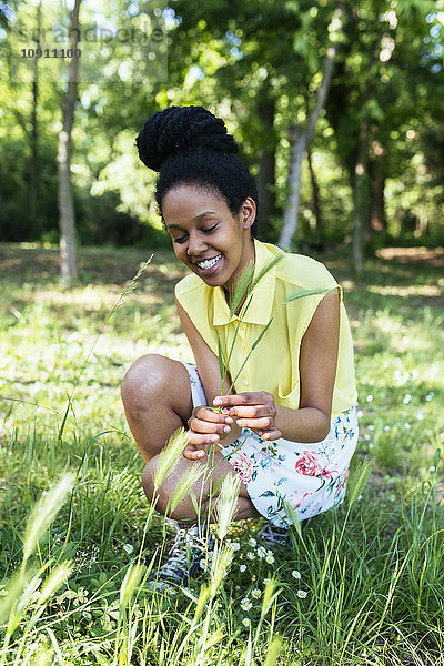Porträt einer lächelnden jungen Frau beim Graspflücken
