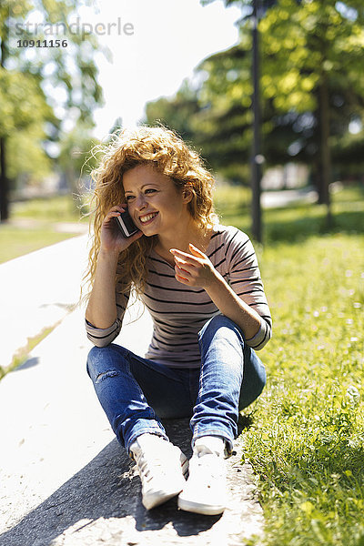 Porträt einer glücklichen Frau beim Telefonieren mit dem Smartphone im Park