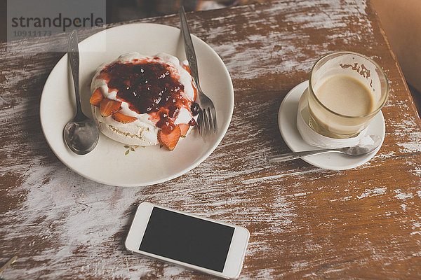 Pavlova Dessert  Handy und Kaffee auf dem Tisch