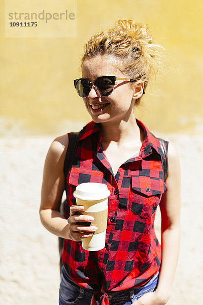 Lächelnde junge Frau mit Kaffee zum Mitnehmen