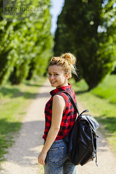 Porträt einer lächelnden Frau mit Rucksack in der Natur
