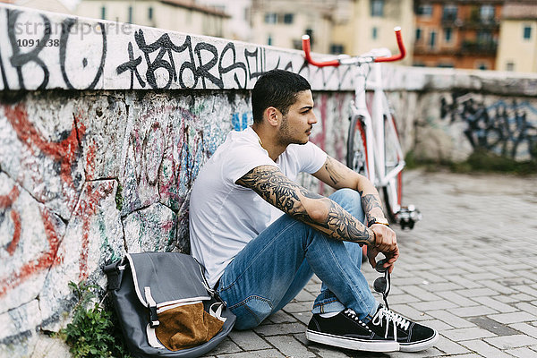 Junger Mann sitzt an der Graffiti-Wand