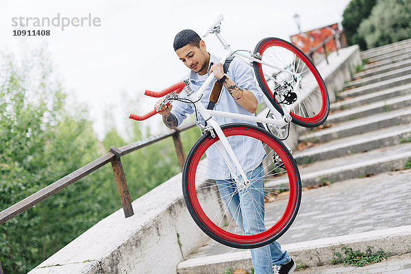 Junger Mann mit Fahrrad auf der Treppe