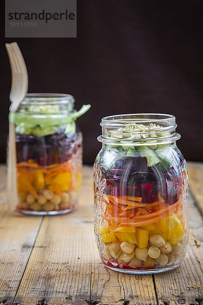 Zwei Gläser Regenbogensalat mit Kichererbsen und verschiedenem Gemüse