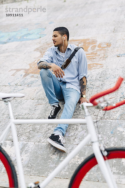 Junger Mann mit einem Fahrrad auf einer Wand sitzend