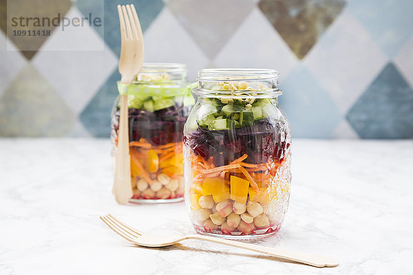 Zwei Gläser Regenbogensalat mit Kichererbsen und verschiedenem Gemüse