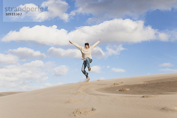 Begeisterte reife Frau beim Springen über die Sanddüne