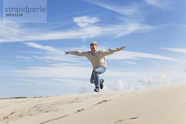 Begeisterte reife Frau beim Springen über die Sanddüne