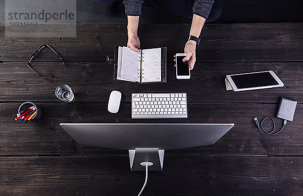 Mann arbeitet am Schreibtisch mit Computer und verschiedenen digitalen Gadgets  Aktualisierung Personal Organizer
