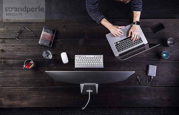 Mann arbeitet am Schreibtisch mit Computer und verschiedenen digitalen Gadgets