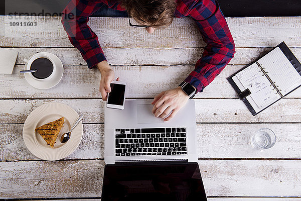 Mann arbeitet am Laptop bei Kaffee und Kuchen