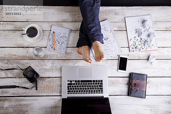 Mann macht eine Pause am Schreibtisch mit Füßen vor dem Laptop