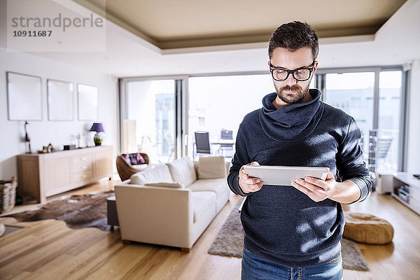 Mann im Wohnzimmer stehend  mit digitalem Tablett