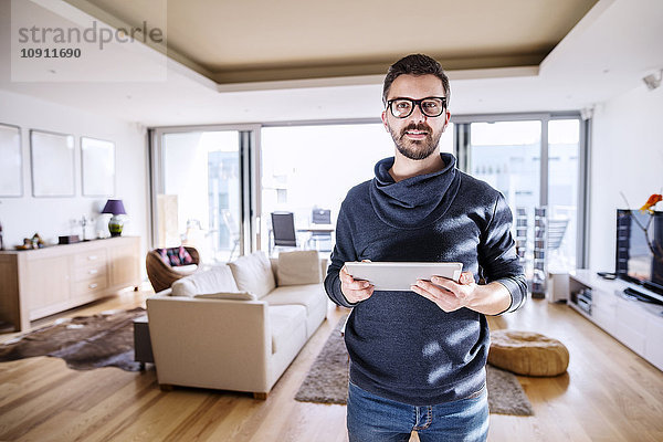 Mann im Wohnzimmer stehend  mit digitalem Tablett