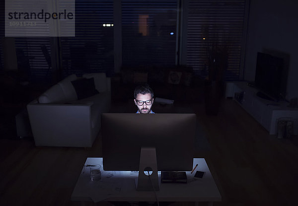 Ein Mann  der nachts mit dem Computer arbeitet.