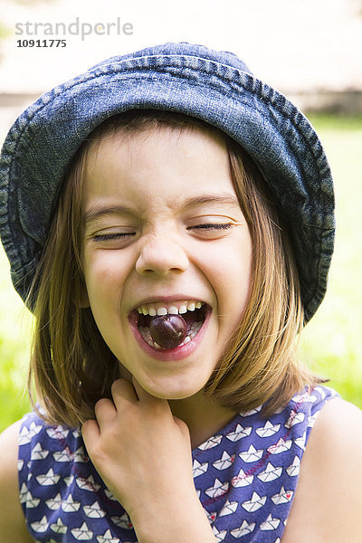 Porträt eines kleinen Mädchens mit Stachelbeere im Mund