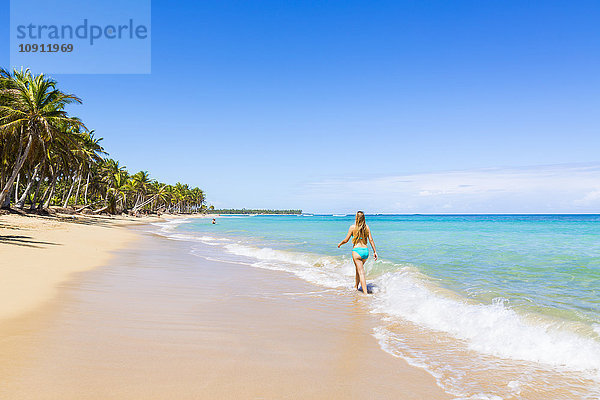 Dominikanische Rebublik  Junge Frau geht am tropischen Strand entlang