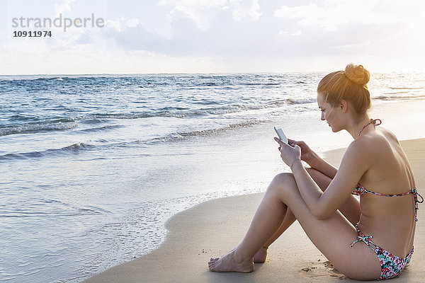 Dominican Rebublic  Junge Frau am tropischen Strand mit mobilem Gerät