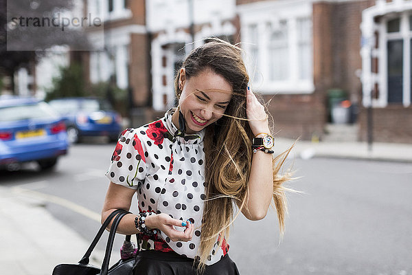 UK  London  Porträt einer lächelnden jungen Frau mit wehendem Haar