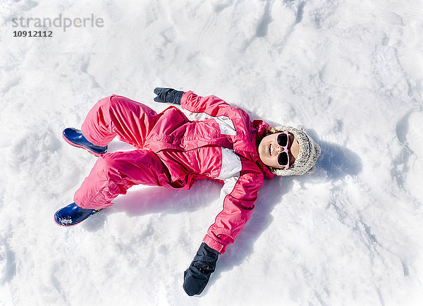 Kleines Mädchen beim Spielen im Schnee  liegend