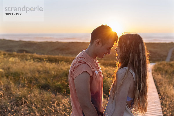Romantisches junges Paar am Strand bei Sonnenuntergang