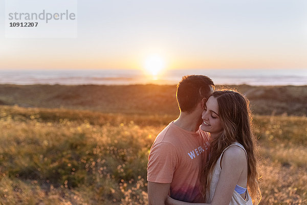 Romantisches junges Paar am Strand bei Sonnenuntergang