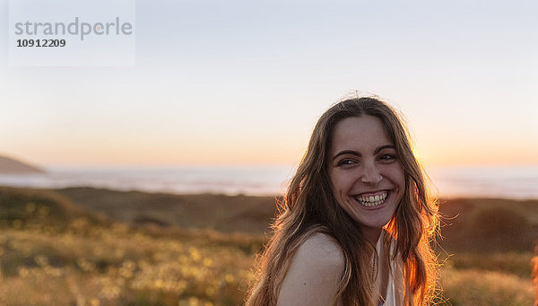 Porträt einer jungen Frau bei Sonnenuntergang am Strand