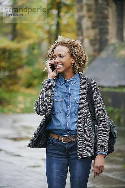 Porträt einer lächelnden Frau beim Telefonieren mit dem Smartphone