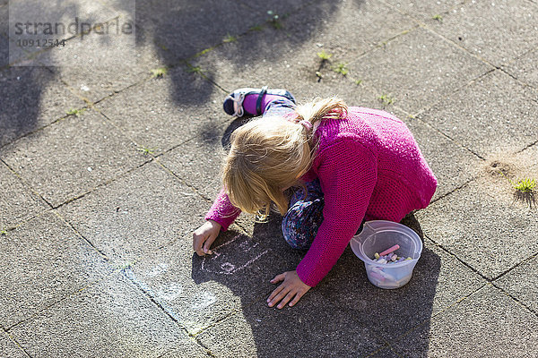 Blondes kleines Mädchen malt mit Buntstiften auf dem Bürgersteig