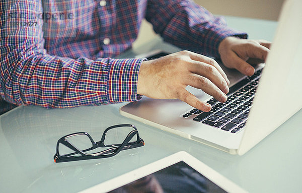 Mann mit Laptop am Schreibtisch  Teilansicht