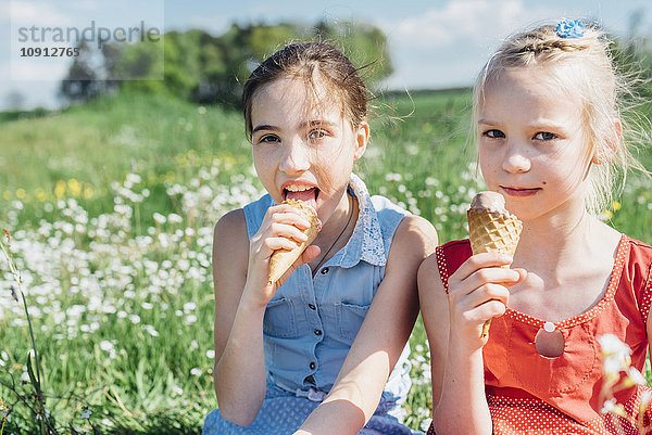 Zwei Mädchen auf der Wiese essen Eistüten