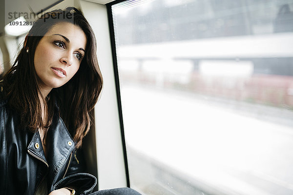 Junge Frau im Zug mit Blick aus dem Fenster