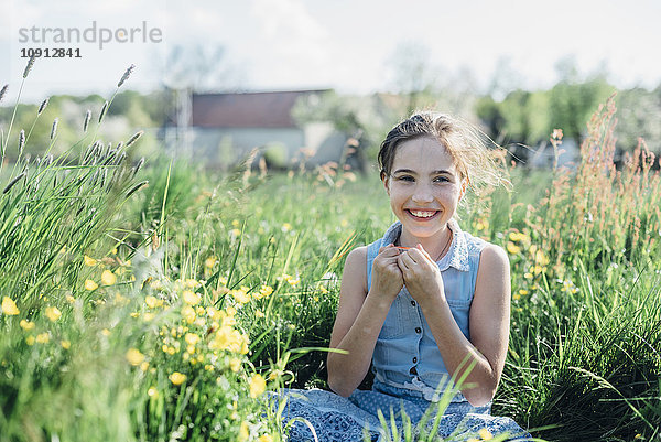 Lächelndes Mädchen auf Blumenwiese sitzend