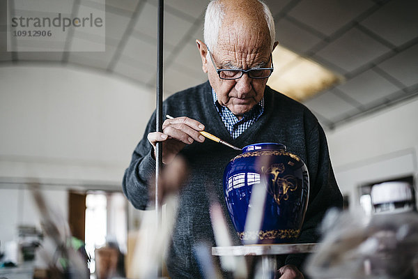 Senior Mann dekoriert Keramikvase in seiner Freizeit