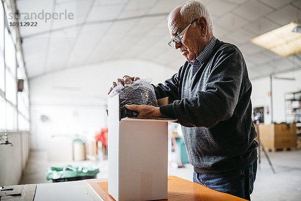 Älterer Mann umhüllt das fertige Keramikstück