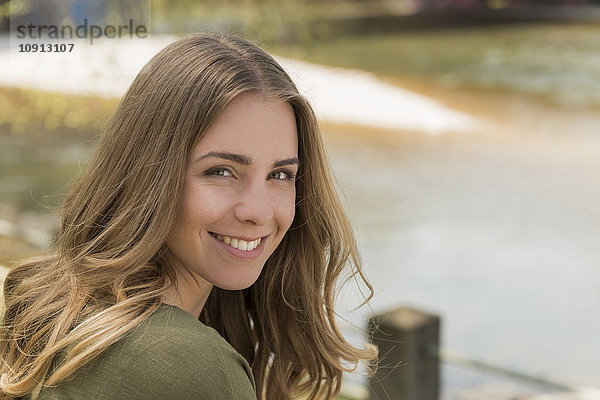 Porträt einer lächelnden jungen Frau am Fluss