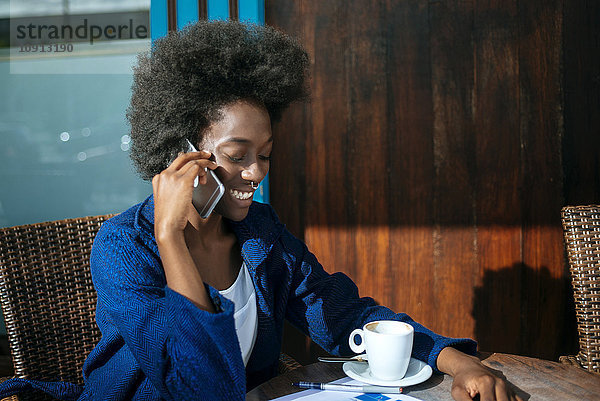 Porträt einer jungen Frau beim Kaffeetrinken im Straßencafé am Handy