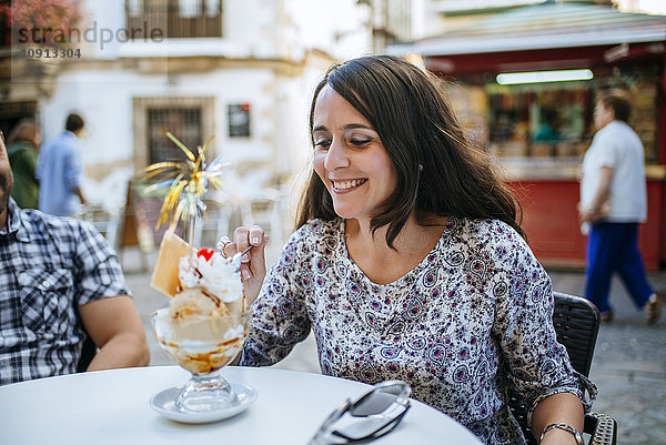 Frau isst Eis in einem Straßencafé