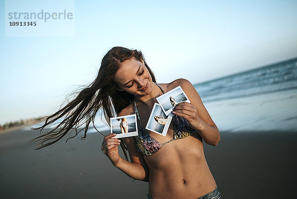 Junge Frau mit Sofortbildern am Strand